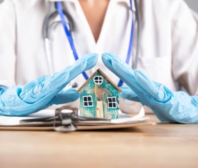 nurse holding hands over wooden house roof